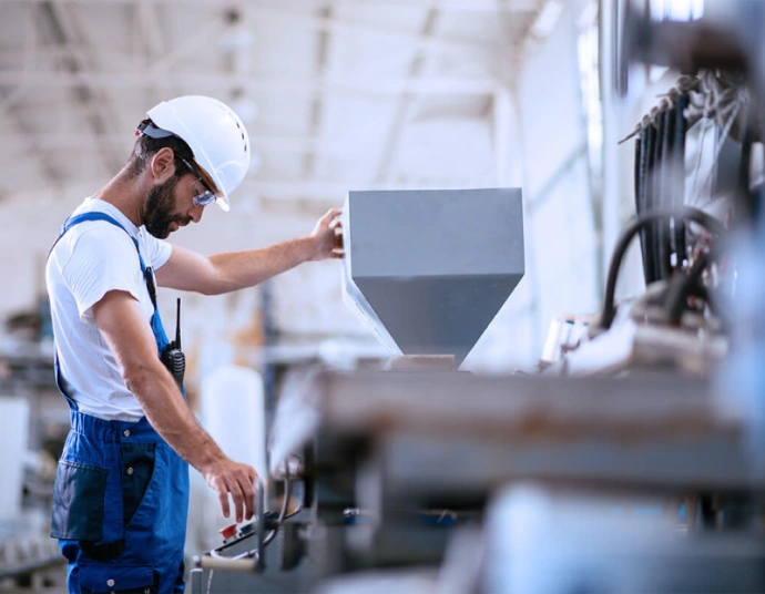 Technician consulting a translated service manual next to industrial equipment